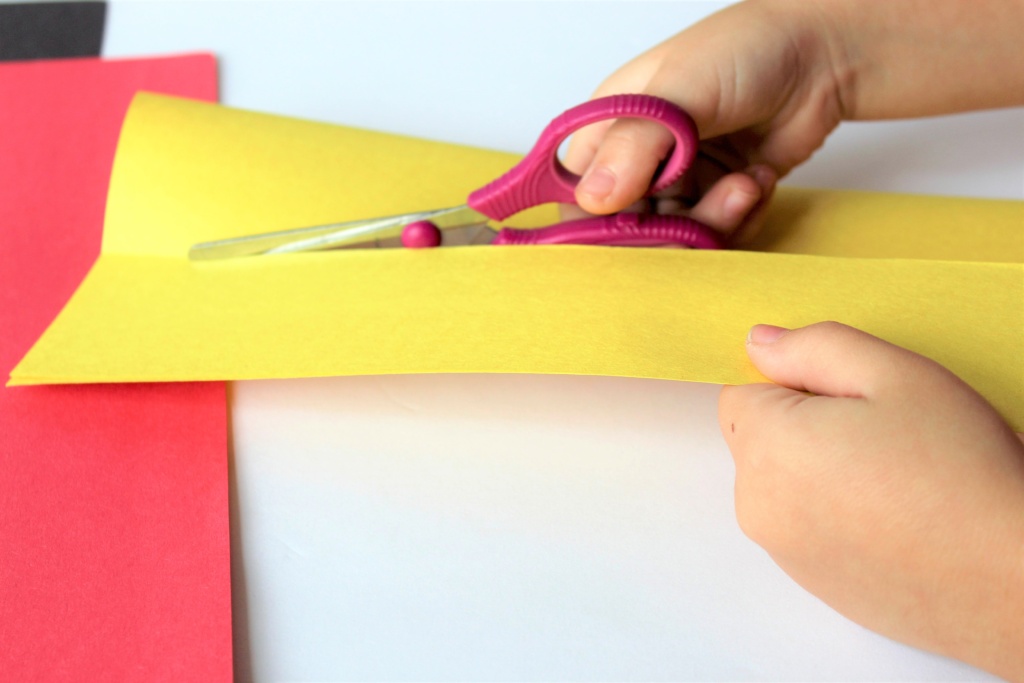child cutting paper with scissors for disney countdown activity